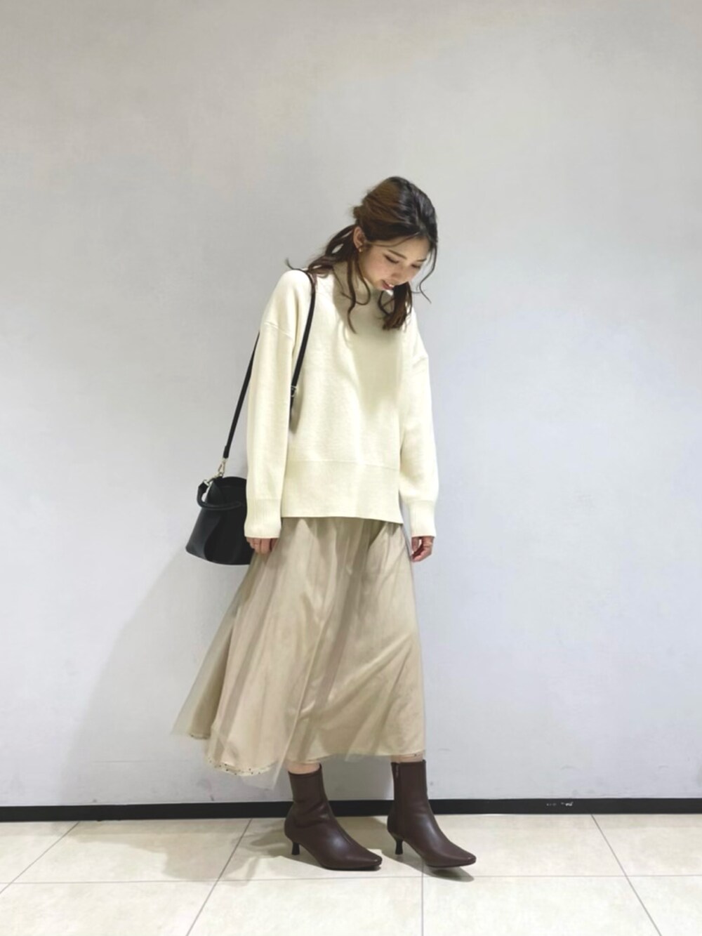 グリーン系のその他アウター、ホワイト系のニット/セーター、ブラック系のショルダーバッグを着用したレディースの冬コーディネートの3枚目の写真