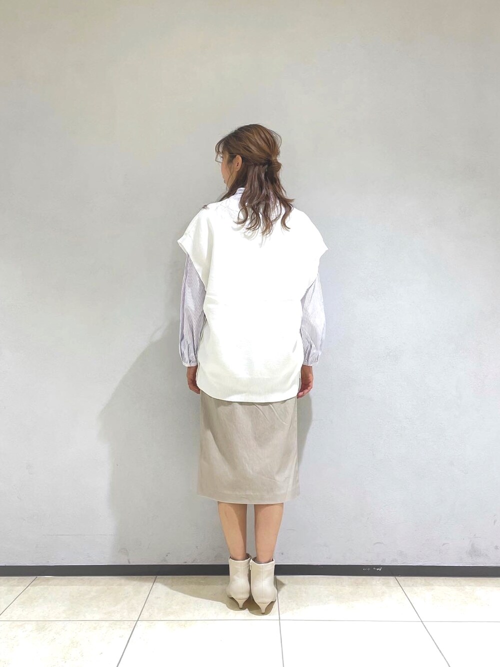 パープル系のシャツ/ブラウス、ホワイト系のベスト、ベージュ系のスカートを着用したレディースの冬コーディネートの3枚目の写真