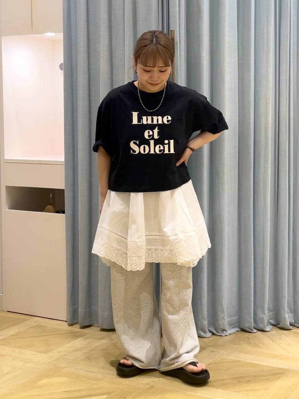 ブラック系のサンダル、ブラック系のTシャツ/カットソー、グレー系のスウェットパンツを着用したレディースの春コーディネートの2枚目の写真