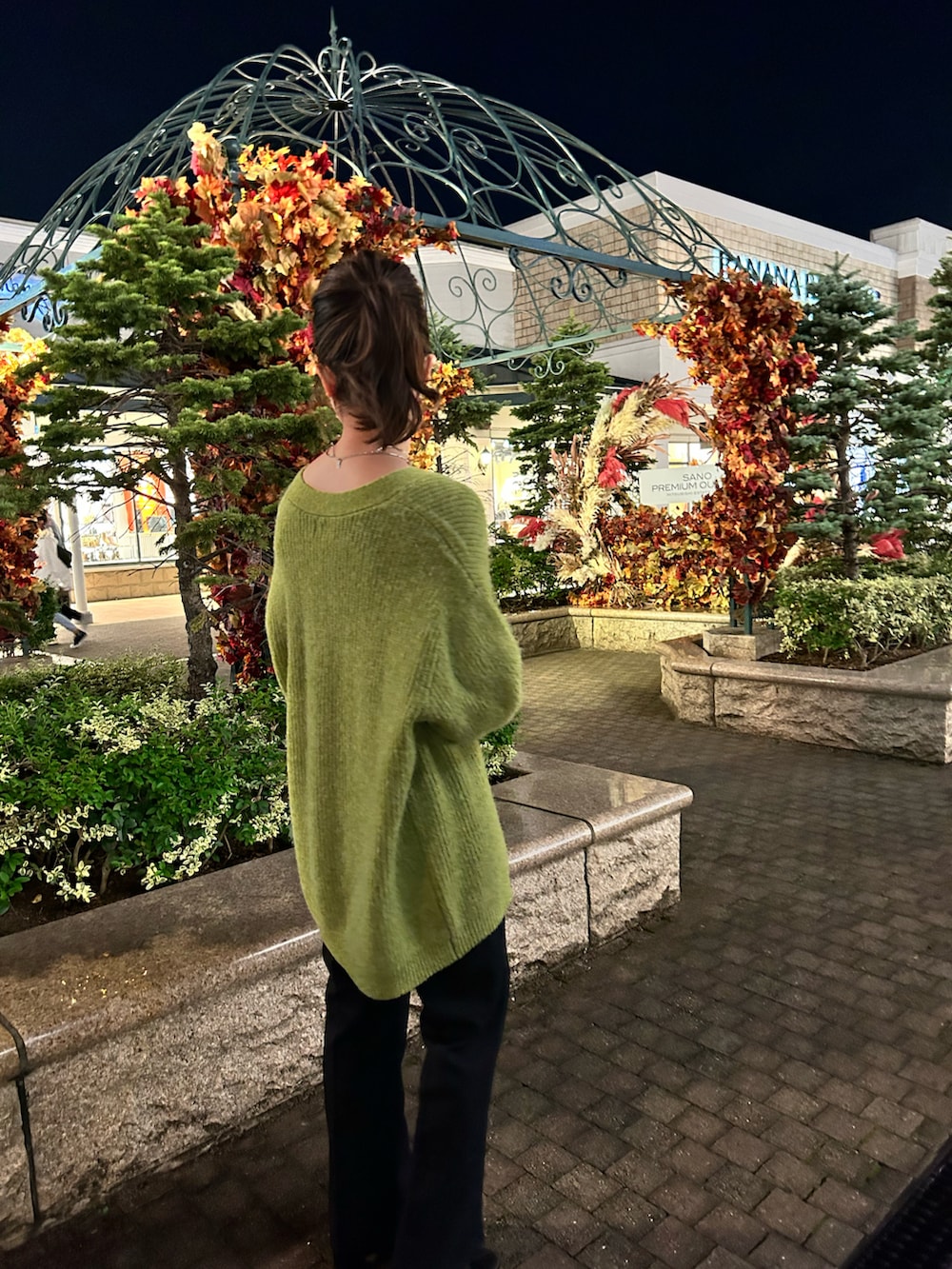 ホワイト系のトートバッグ、ブラック系のスラックス、グリーン系のカーディガン/ボレロを着用したレディースの秋コーディネートの2枚目の写真