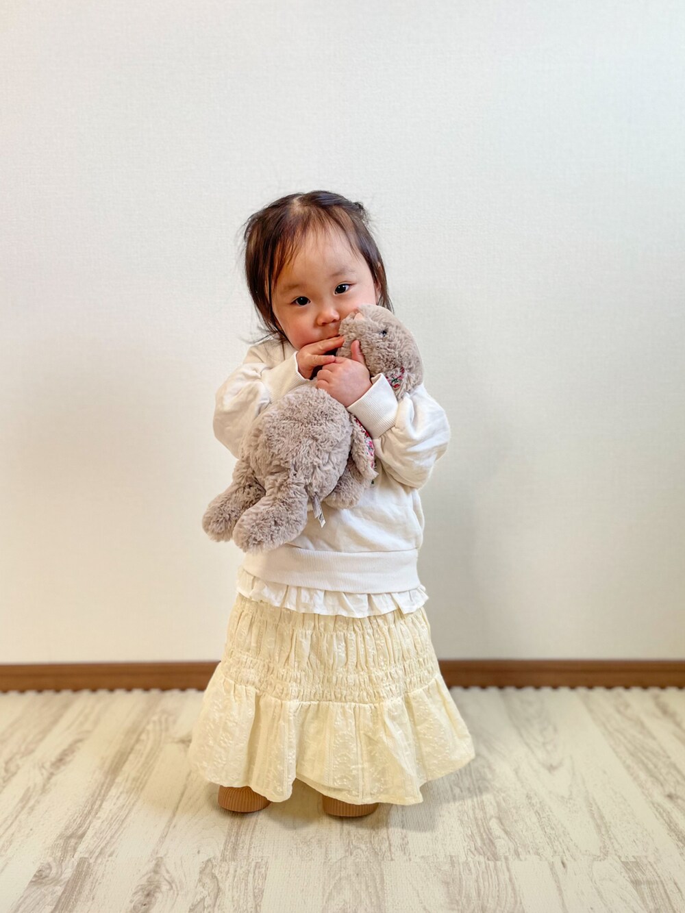 ホワイト系のスウェット、ベージュ系のスカート、ホワイト系のスニーカーを着用したキッズの春コーディネートの3枚目の写真