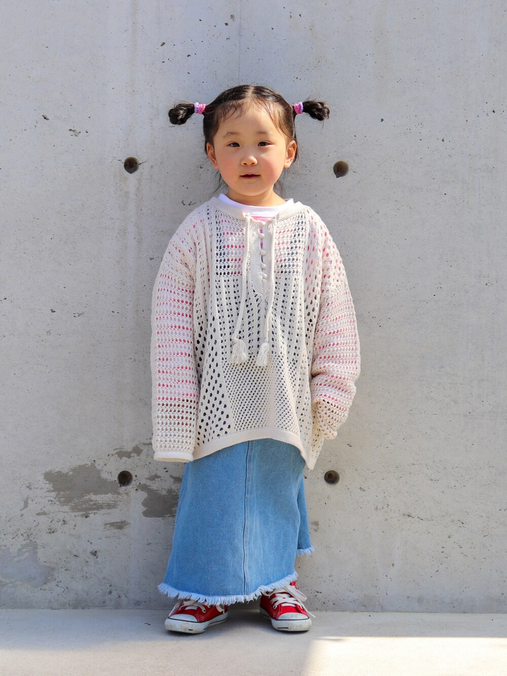 ベージュ系のニット/セーター、ピンク系のTシャツ/カットソー、ブルー系のジャンパースカートを着用したキッズの春コーディネートの2枚目の写真