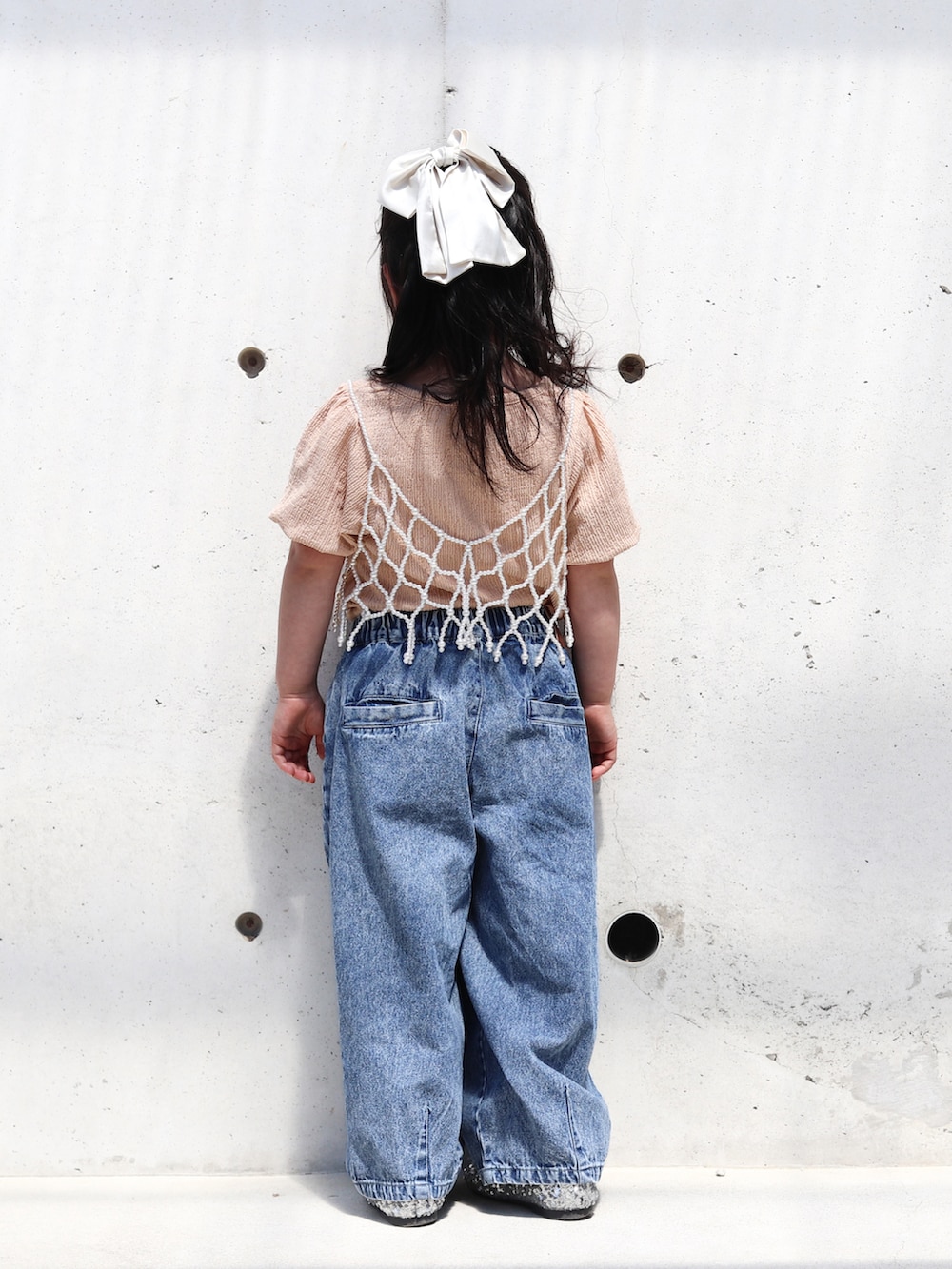 ピンク系のTシャツ/カットソー、ブルー系のデニムパンツ、シルバー系のバレエシューズを着用したキッズの春コーディネートの3枚目の写真