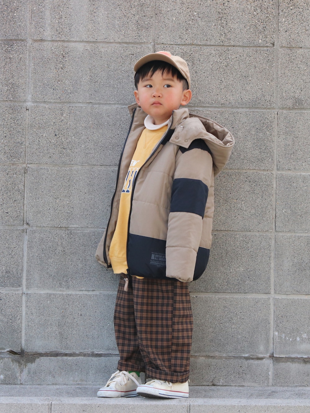 ベージュ系のダウンジャケット/コート、イエロー系のスウェット、ホワイト系のニット/セーターを着用したキッズの冬コーディネートの3枚目の写真