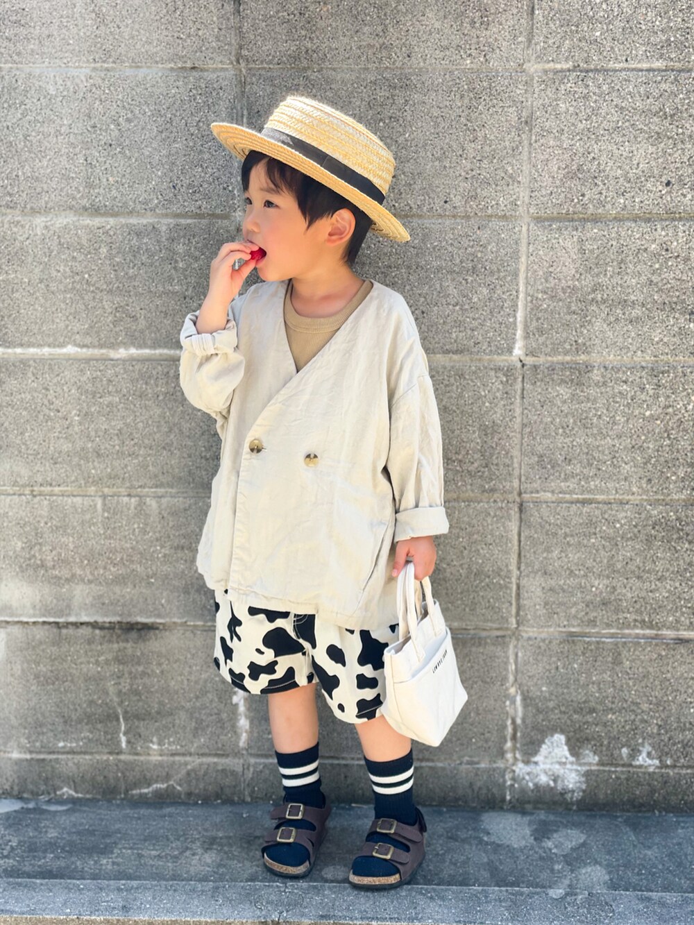 ホワイト系のノーカラージャケット、ベージュ系のタンクトップ、ブラック系のその他パンツを着用したキッズの春コーディネートの2枚目の写真