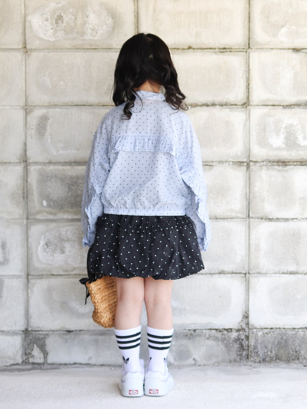 ブルー系のナイロンジャケット、ブラック系のスカート、ブラック系のかごバッグを着用したキッズの春コーディネートの4枚目の写真