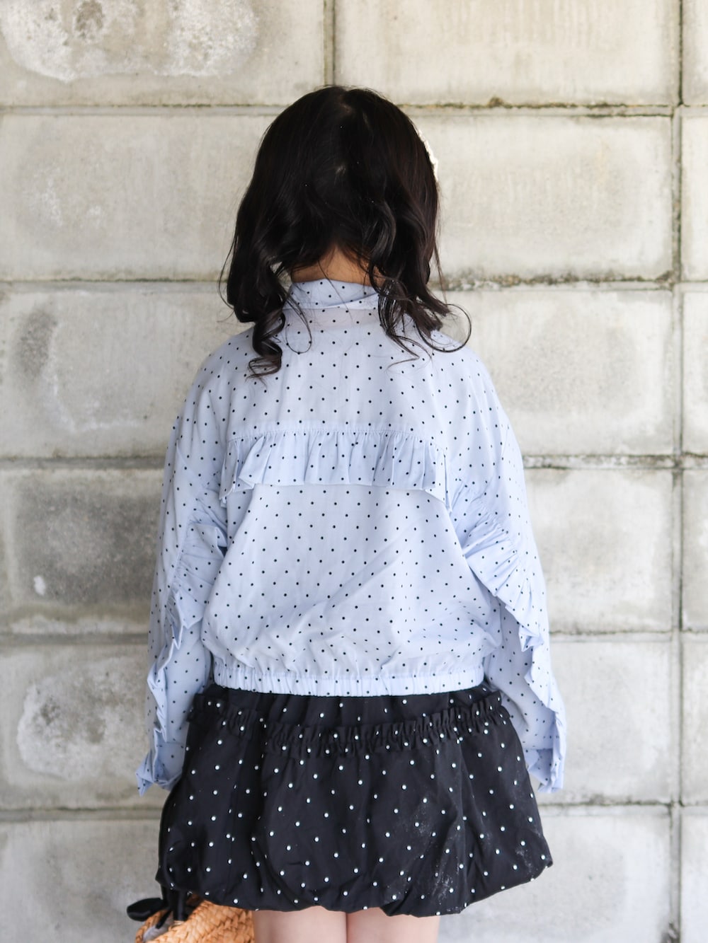 ブルー系のナイロンジャケット、ブラック系のスカート、ブラック系のかごバッグを着用したキッズの春コーディネートの5枚目の写真