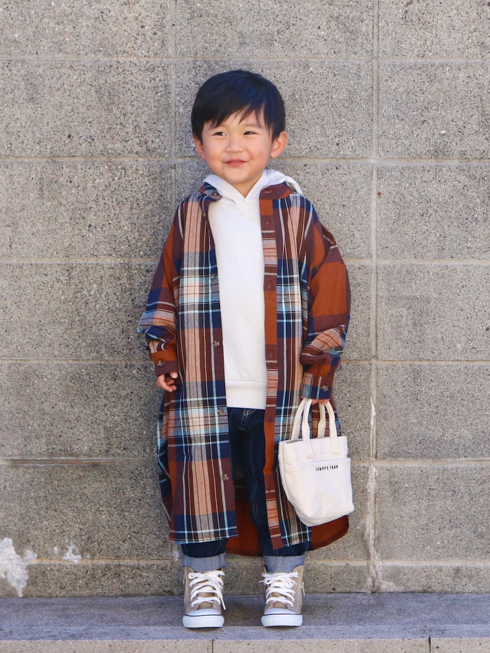 ブラウン系のシャツ/ブラウス、ホワイト系のパーカー、ブルー系のデニムパンツを着用したキッズの秋コーディネートの2枚目の写真