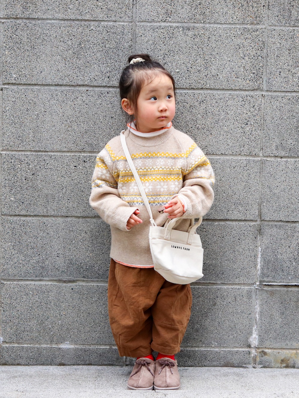 ベージュ系のニット/セーター、ホワイト系のTシャツ/カットソー、ブラウン系のチノパンツを着用したキッズの冬コーディネートの2枚目の写真