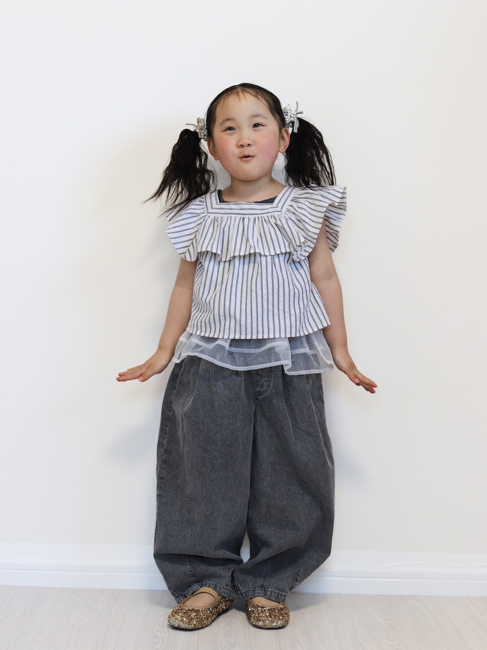 ブラック系のセットアップ、ブラック系のデニムパンツ、ゴールド系のバレエシューズを着用したキッズの春コーディネートの2枚目の写真