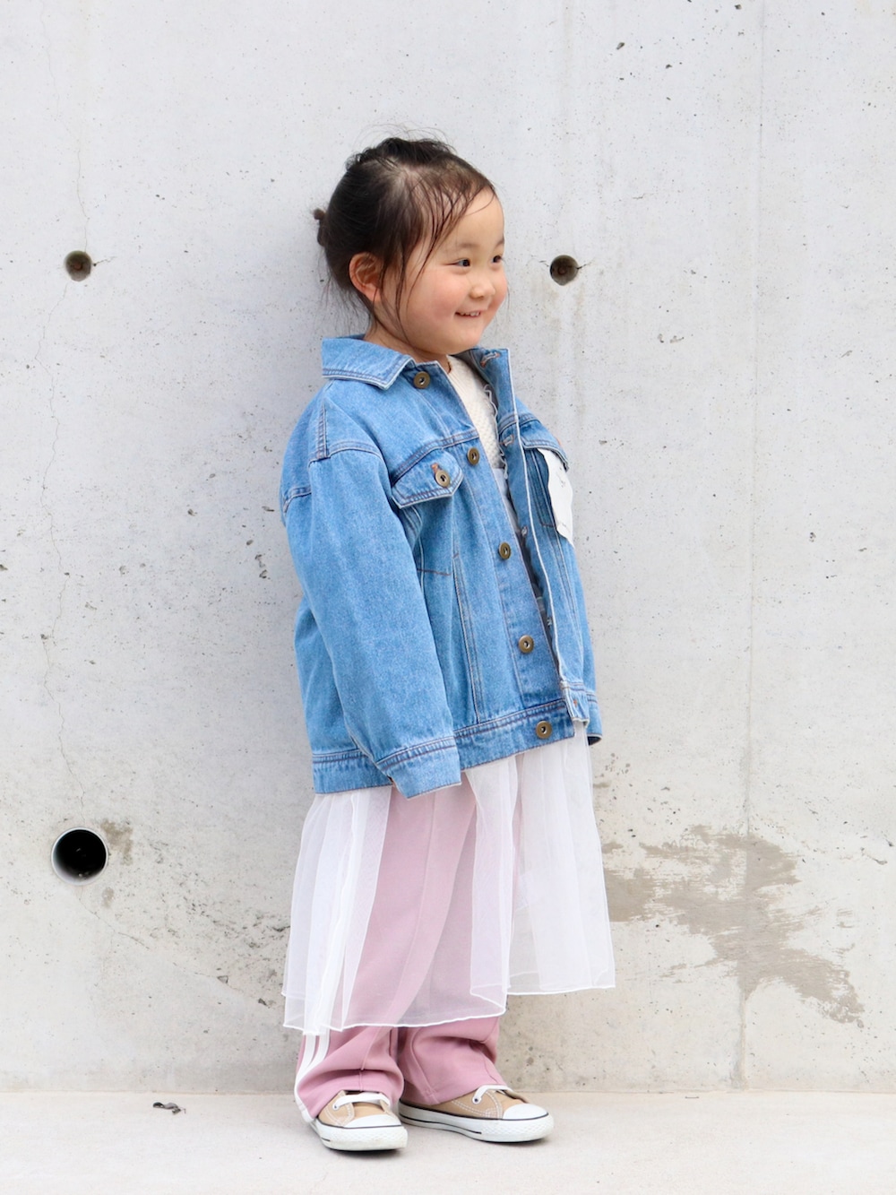ブルー系のデニムジャケット、ホワイト系のニット/セーター、ホワイト系のワンピースを着用したキッズの冬コーディネートの2枚目の写真
