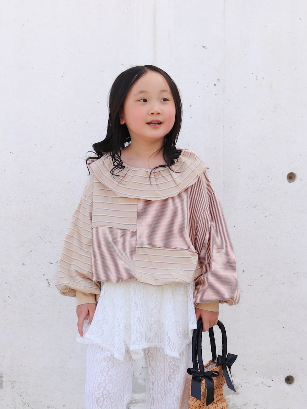 ホワイト系のその他パンツ、ベージュ系のTシャツ/カットソー、ブラック系のかごバッグを着用したキッズの春コーディネートの2枚目の写真