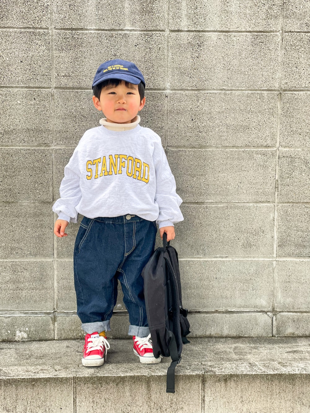 グレー系のスウェット、ホワイト系のニット/セーター、ブルー系のデニムパンツを着用したキッズの冬コーディネートの2枚目の写真