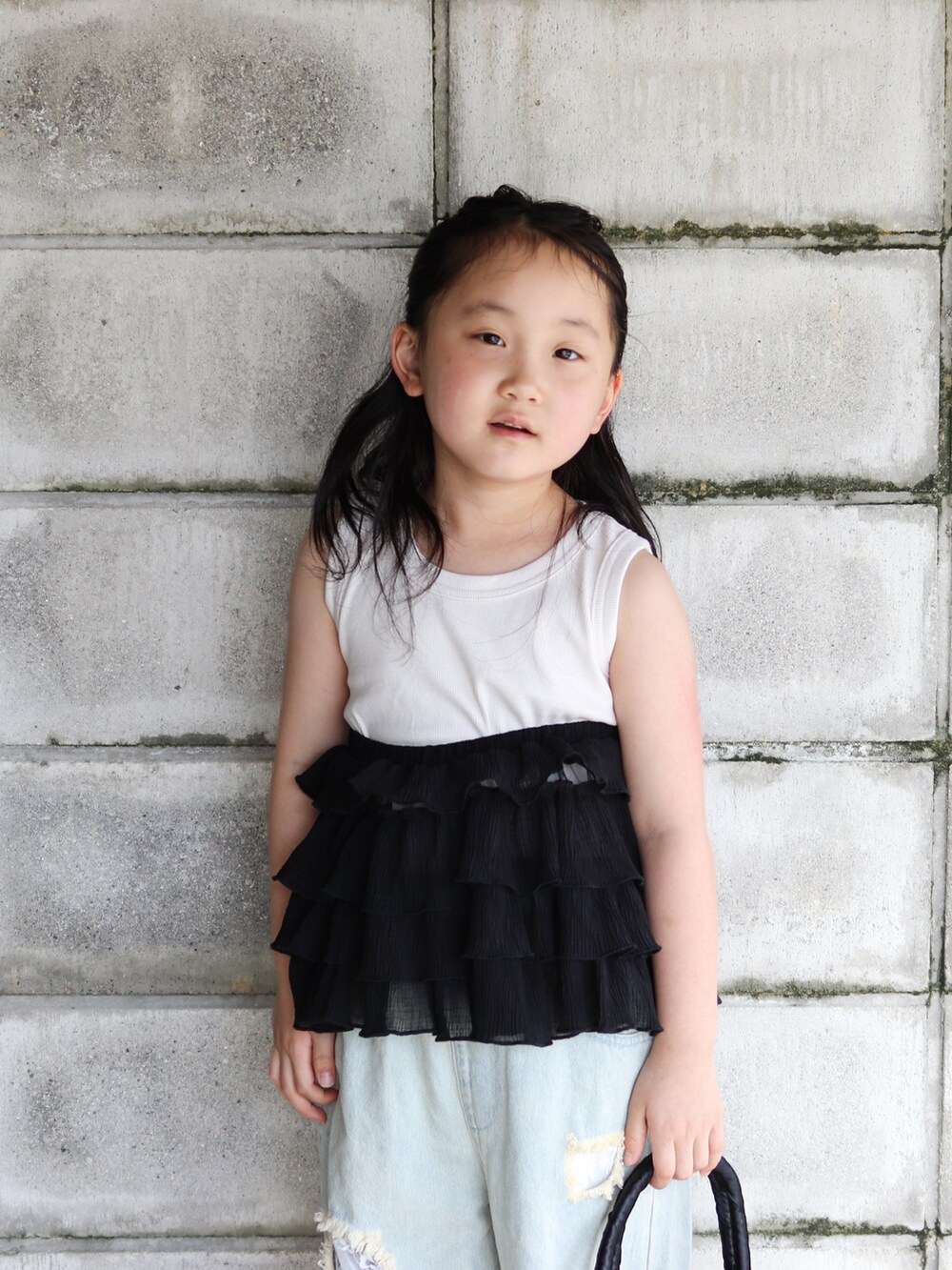 ブルー系のデニムパンツ、ブラック系のかごバッグ、ベージュ系のサンダルを着用したキッズの夏コーディネートの4枚目の写真