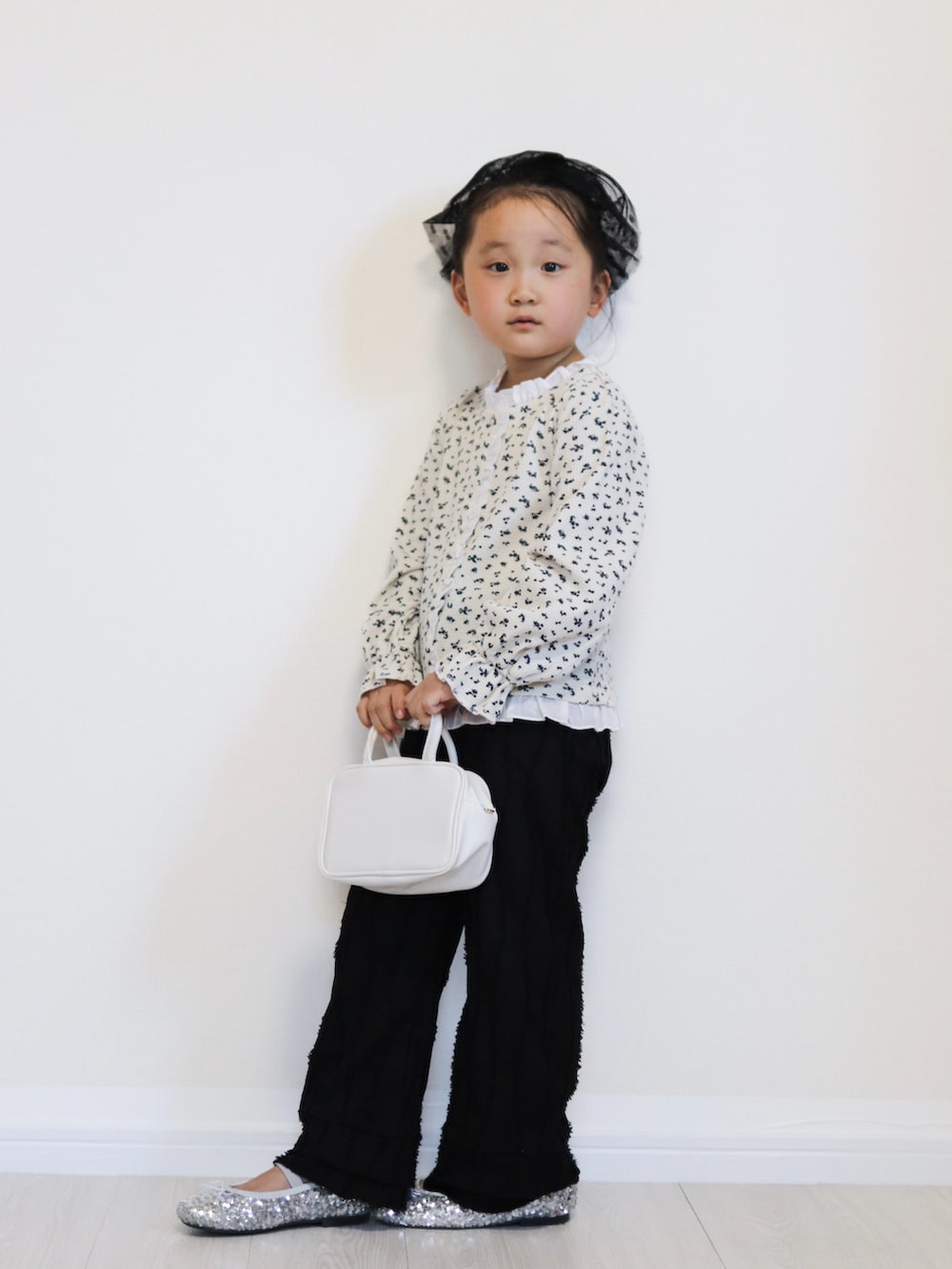 ホワイト系のカーディガン/ボレロ、シルバー系のバレエシューズ、ブラック系のその他パンツを着用したキッズの秋コーディネートの3枚目の写真