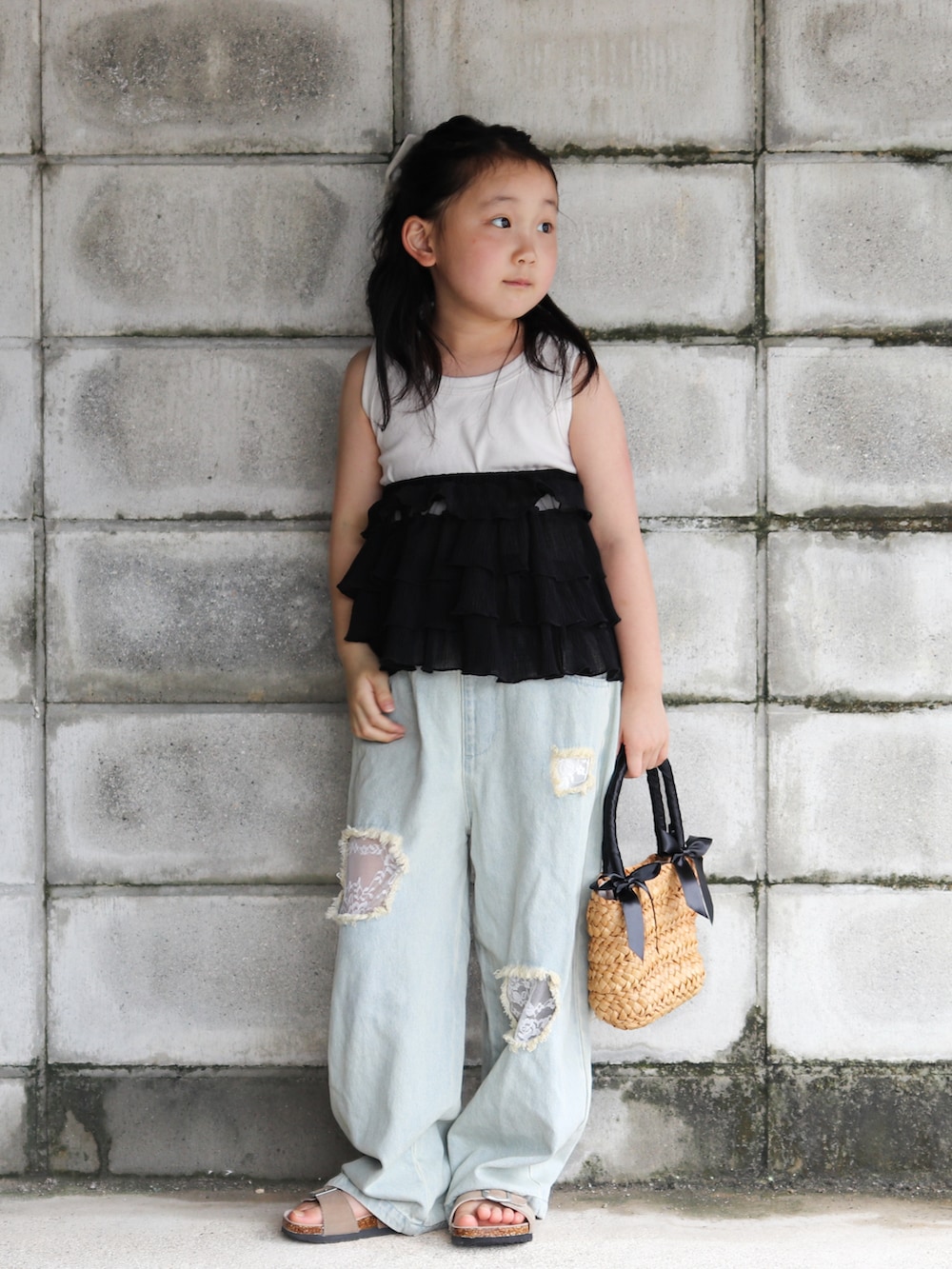 ブルー系のデニムパンツ、ブラック系のかごバッグ、ベージュ系のサンダルを着用したキッズの夏コーディネートの5枚目の写真