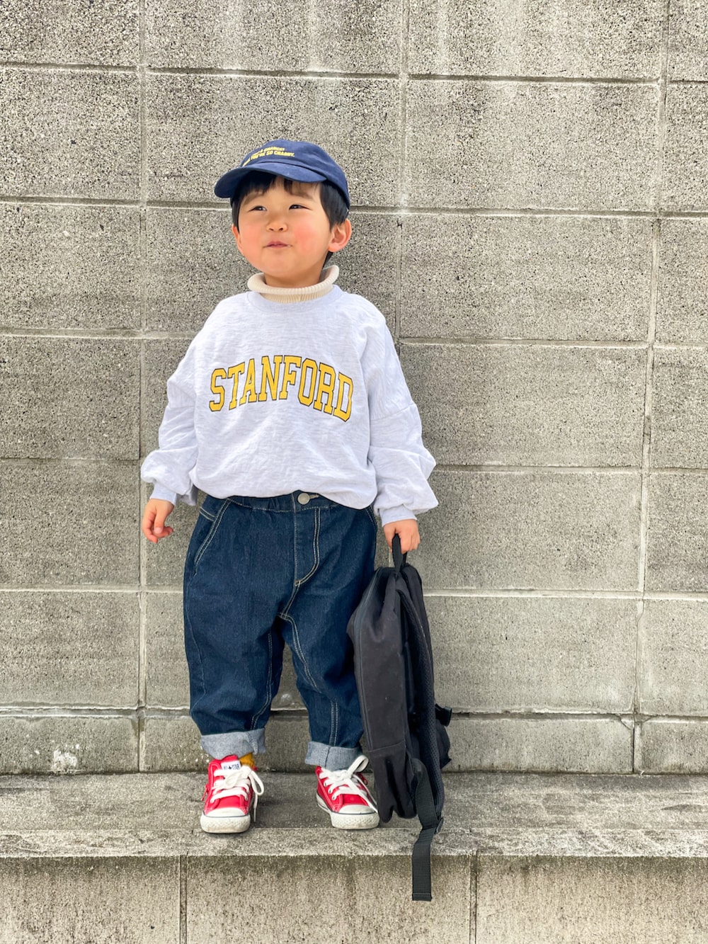 グレー系のスウェット、ホワイト系のニット/セーター、ブルー系のデニムパンツを着用したキッズの冬コーディネートの3枚目の写真