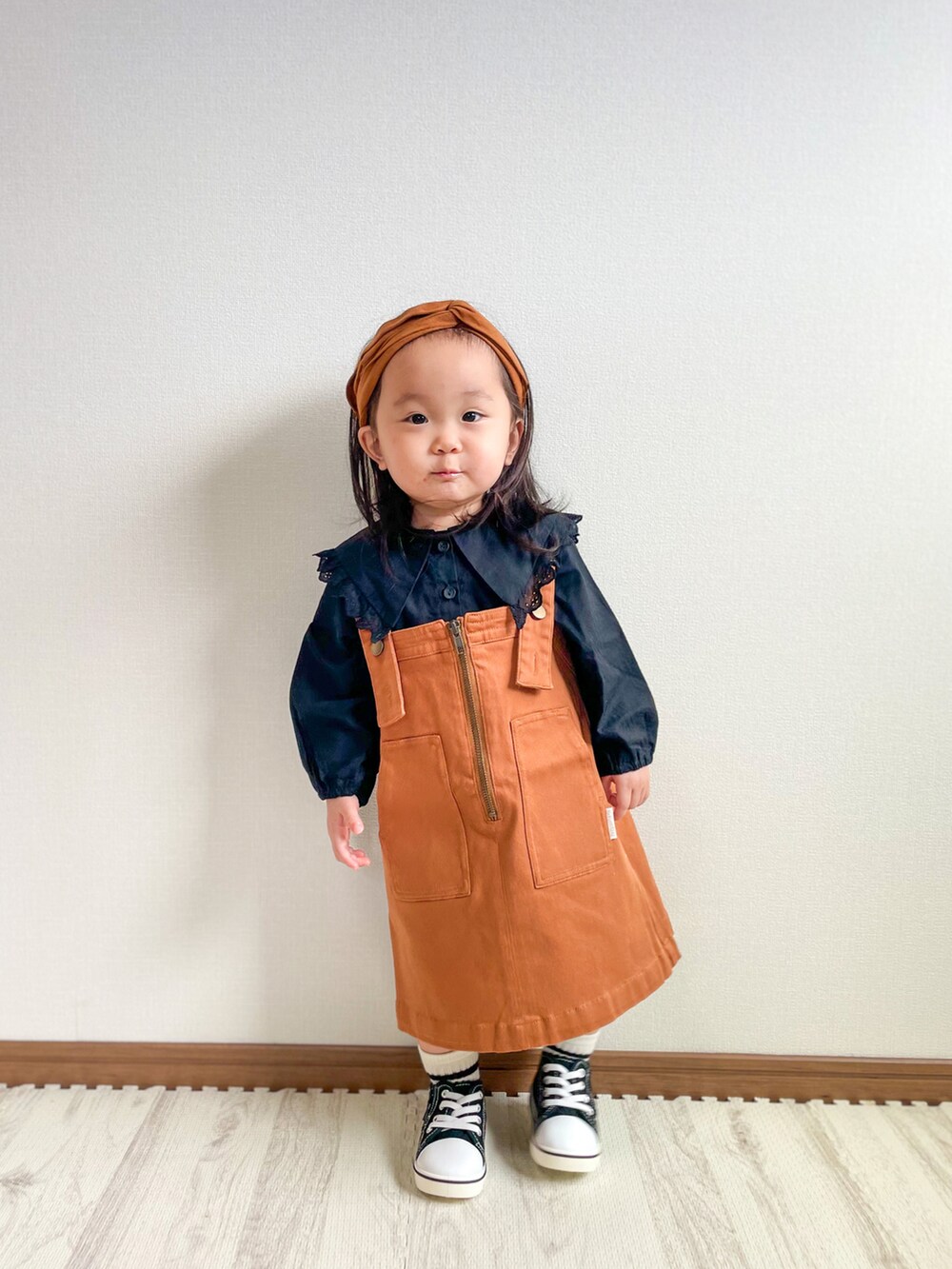 ブラック系のシャツ/ブラウス、イエロー系のジャンパースカート、ブラック系のスニーカーを着用したキッズの秋コーディネートの3枚目の写真