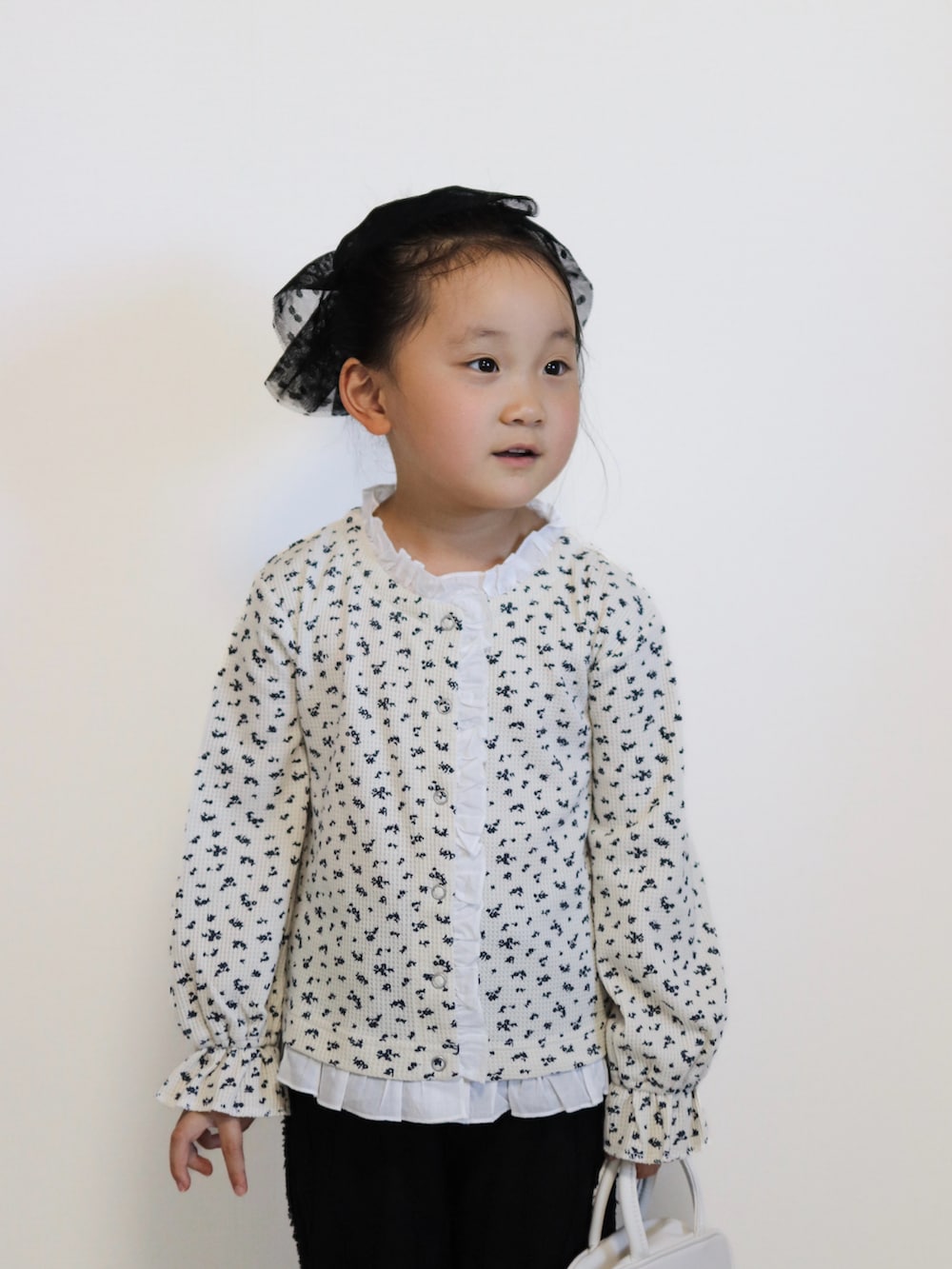 ホワイト系のカーディガン/ボレロ、シルバー系のバレエシューズ、ブラック系のその他パンツを着用したキッズの秋コーディネートの5枚目の写真