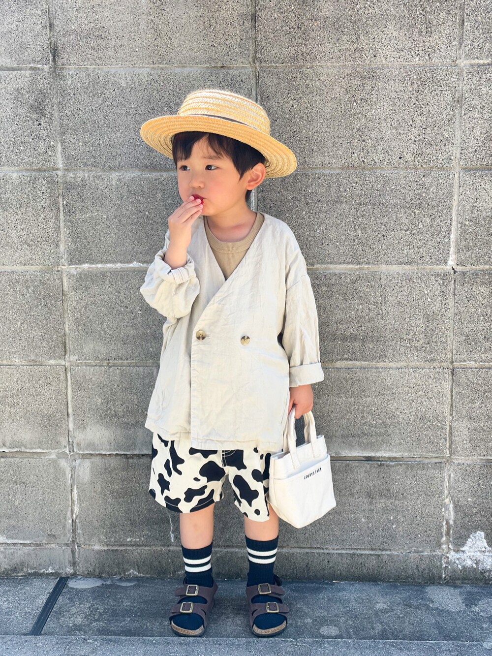 ホワイト系のノーカラージャケット、ベージュ系のタンクトップ、ブラック系のその他パンツを着用したキッズの春コーディネートの3枚目の写真