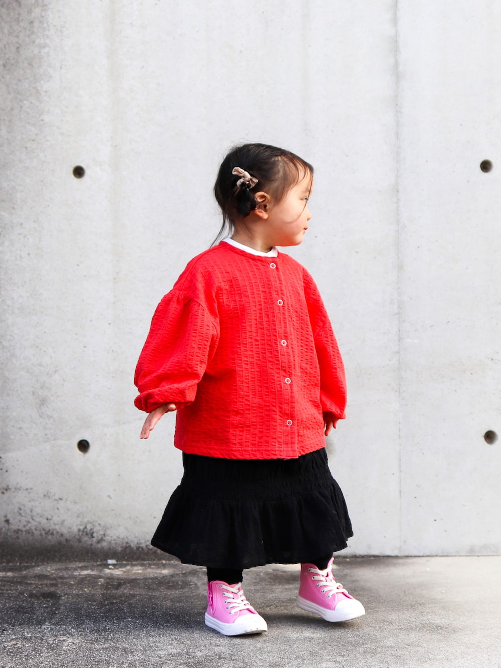 レッド系のカーディガン/ボレロ、ホワイト系のシャツ/ブラウス、ブラック系のスカートを着用したキッズの冬コーディネートの3枚目の写真