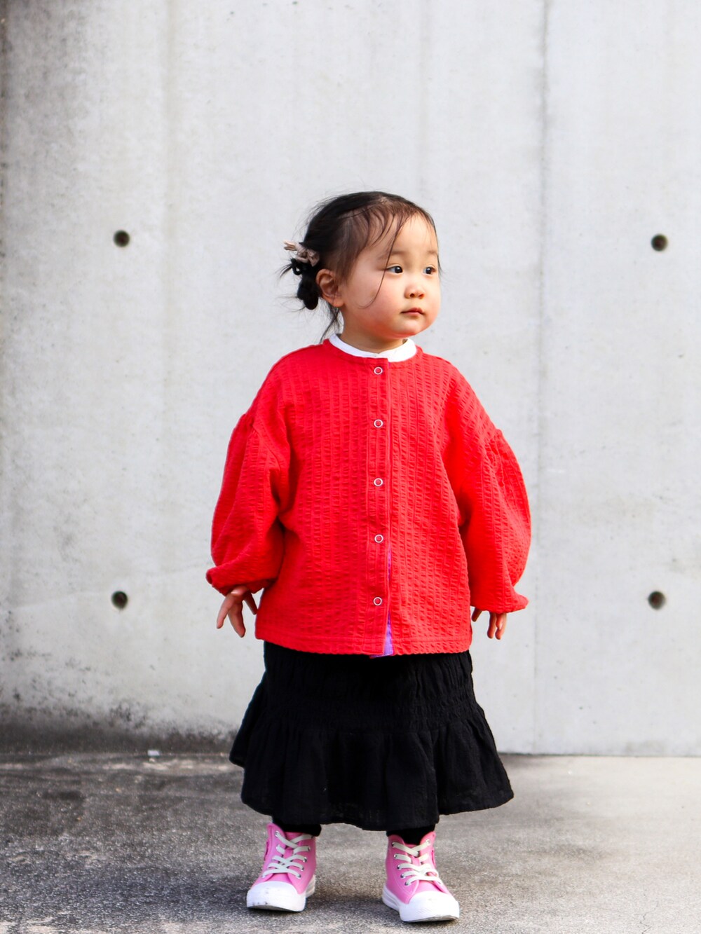 レッド系のカーディガン/ボレロ、ホワイト系のシャツ/ブラウス、ブラック系のスカートを着用したキッズの冬コーディネートの2枚目の写真