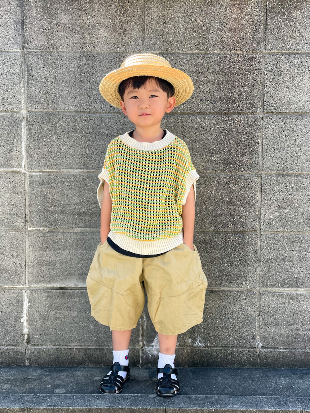 グリーン系のベスト、ブラック系のタンクトップ、ベージュ系のパンツを着用したキッズの夏コーディネートの2枚目の写真