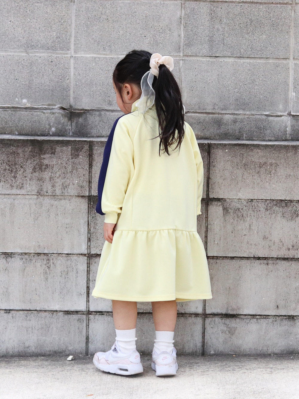 イエロー系のワンピース、ピンク系のスニーカー、ホワイト系のソックス/靴下を着用したキッズの冬コーディネートの4枚目の写真