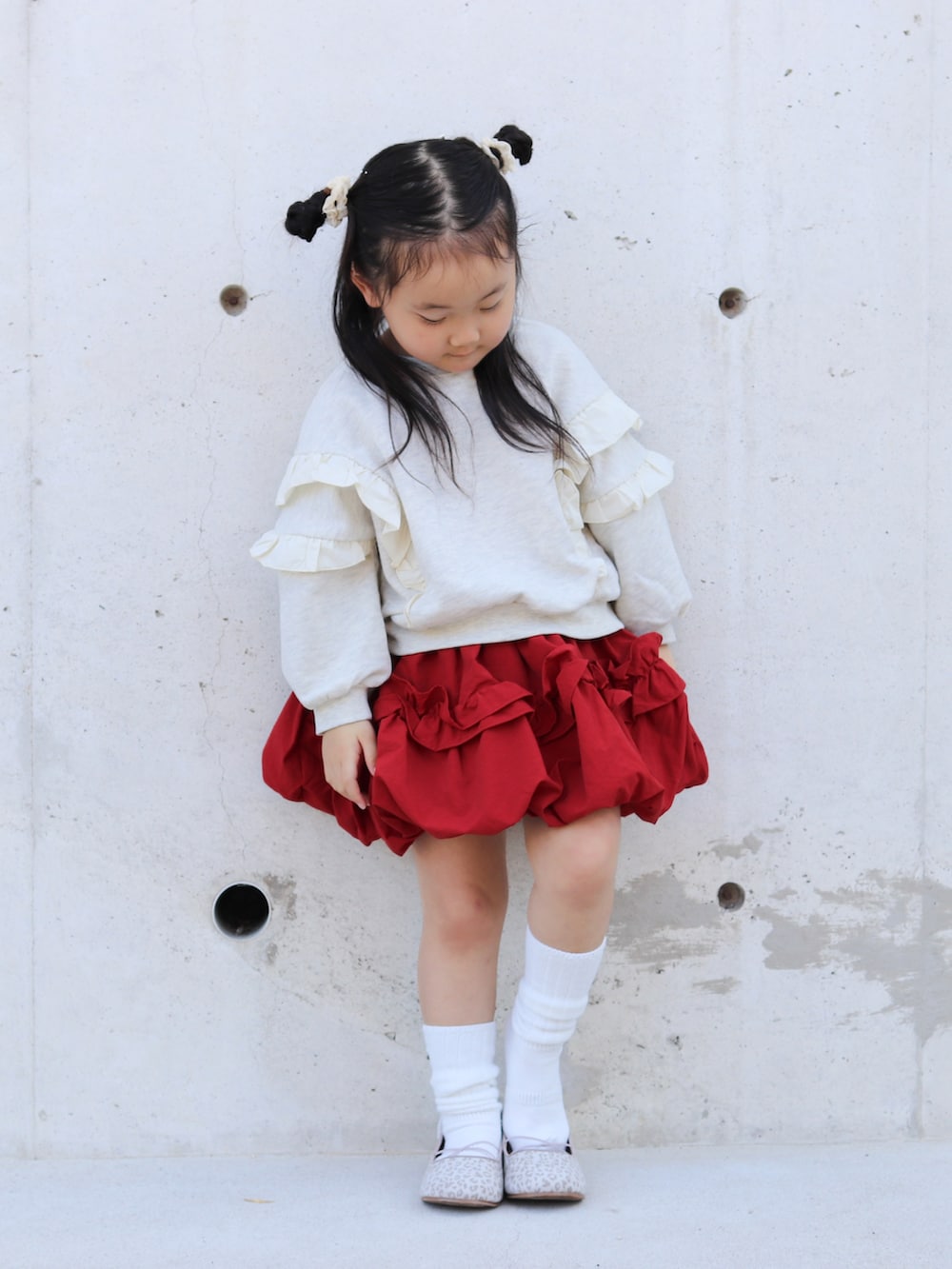 ベージュ系のスウェット、レッド系のスカート、ベージュ系のバレエシューズを着用したキッズの秋コーディネートの2枚目の写真