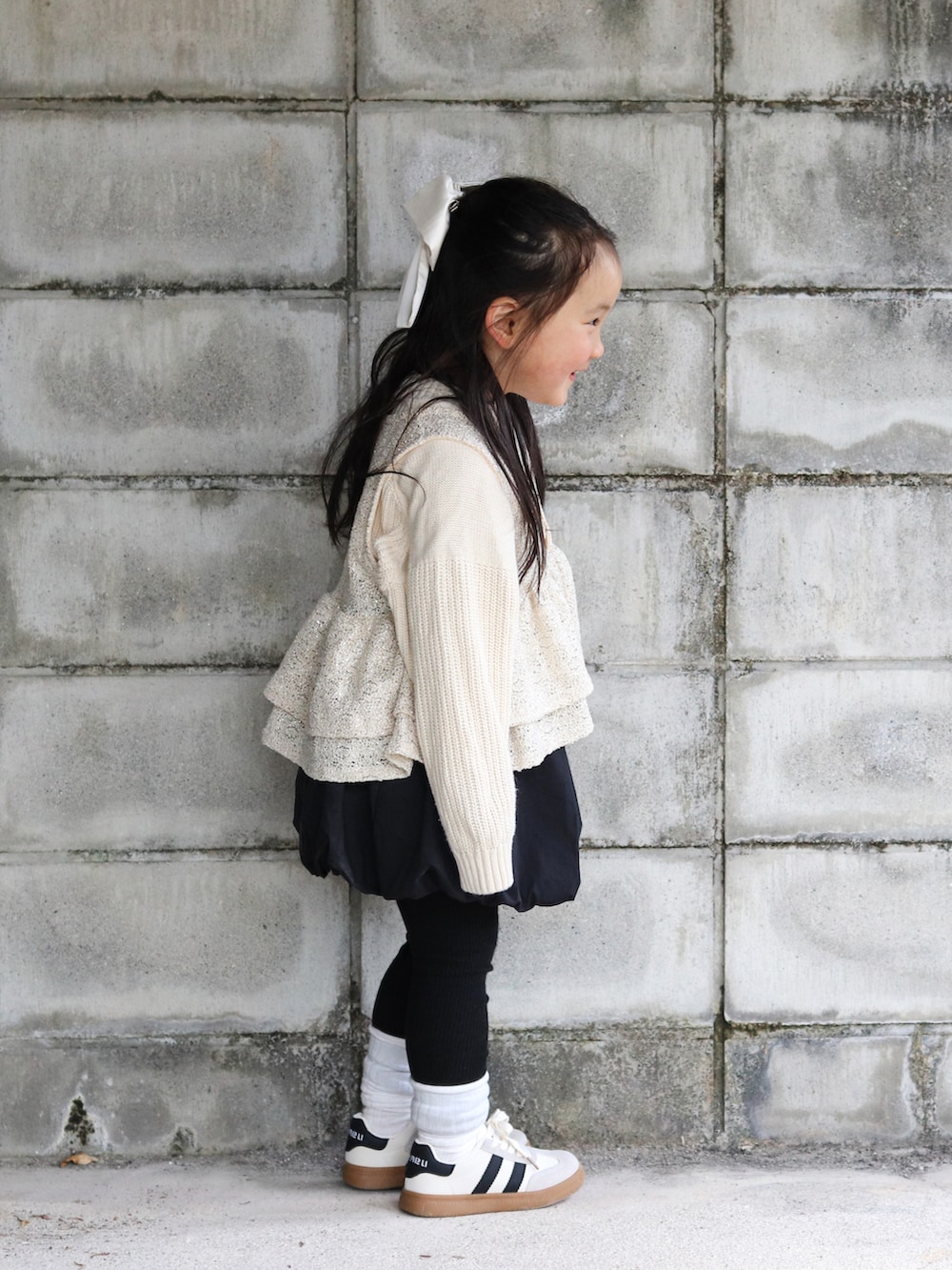 ホワイト系のニット/セーター、ベージュ系のベスト、ブラック系のスカートを着用したキッズの冬コーディネートの3枚目の写真
