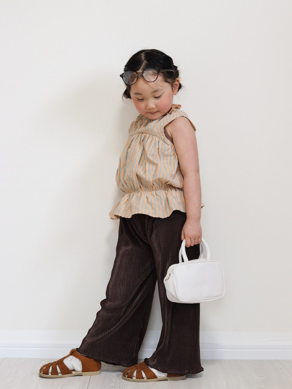 オレンジ系のセットアップ、ブラウン系のその他パンツ、イエロー系のサンダルを着用したキッズの春コーディネートの2枚目の写真