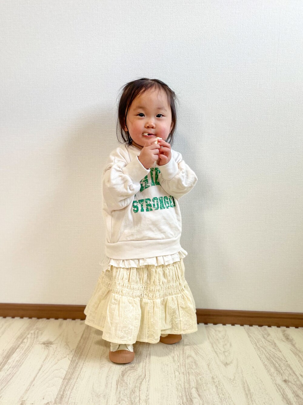 ホワイト系のスウェット、ベージュ系のスカート、ホワイト系のスニーカーを着用したキッズの春コーディネートの4枚目の写真