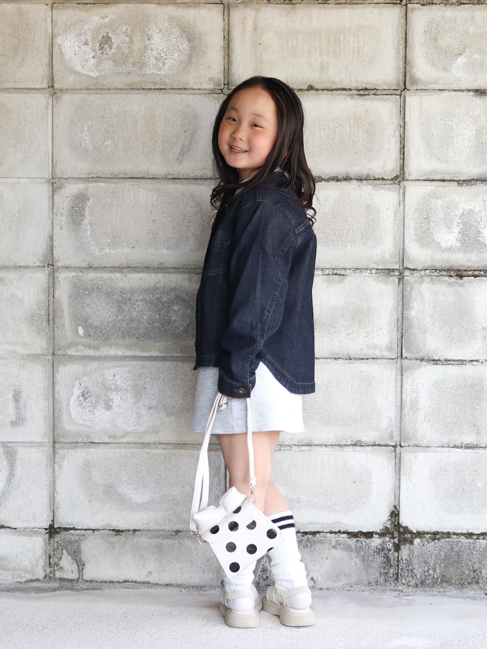 ブルー系のブルゾン、ホワイト系のワンピース、ホワイト系のショルダーバッグを着用したキッズの春コーディネートの4枚目の写真
