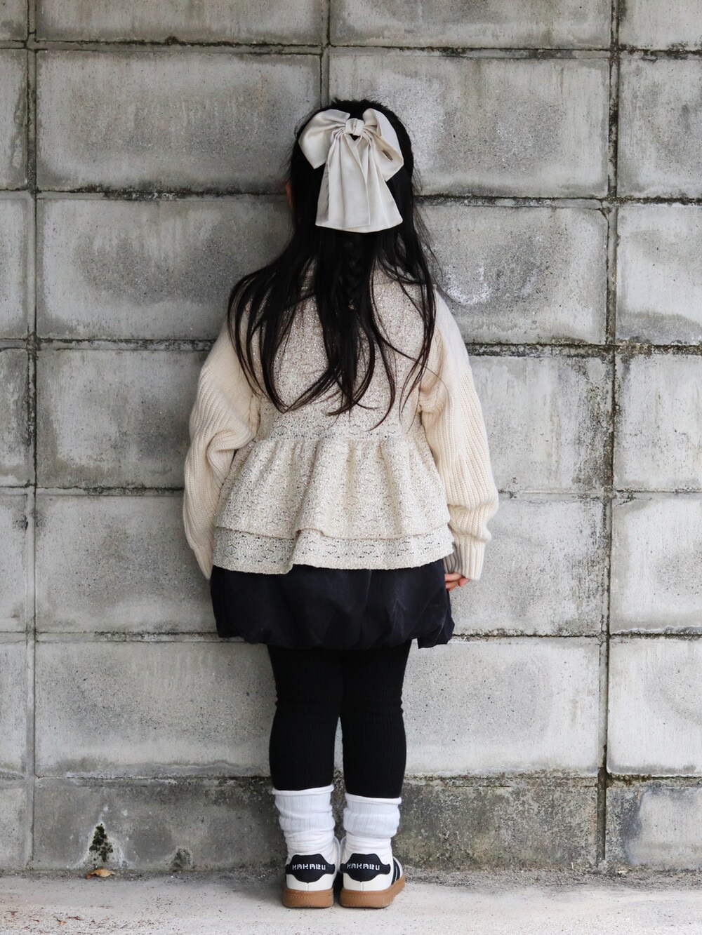 ホワイト系のニット/セーター、ベージュ系のベスト、ブラック系のスカートを着用したキッズの冬コーディネートの4枚目の写真