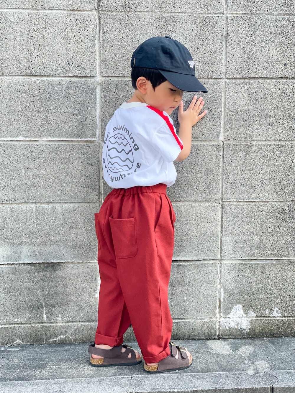 ホワイト系のTシャツ/カットソー、レッド系のその他パンツ、ブラウン系のサンダルを着用したキッズの夏コーディネートの3枚目の写真