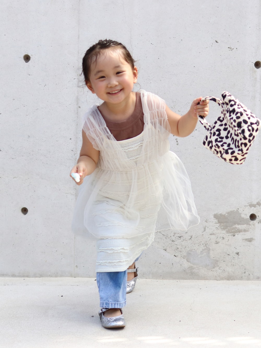 ホワイト系のチュニック、ブラウン系のタンクトップ、ホワイト系のワンピースを着用したキッズの夏コーディネートの3枚目の写真