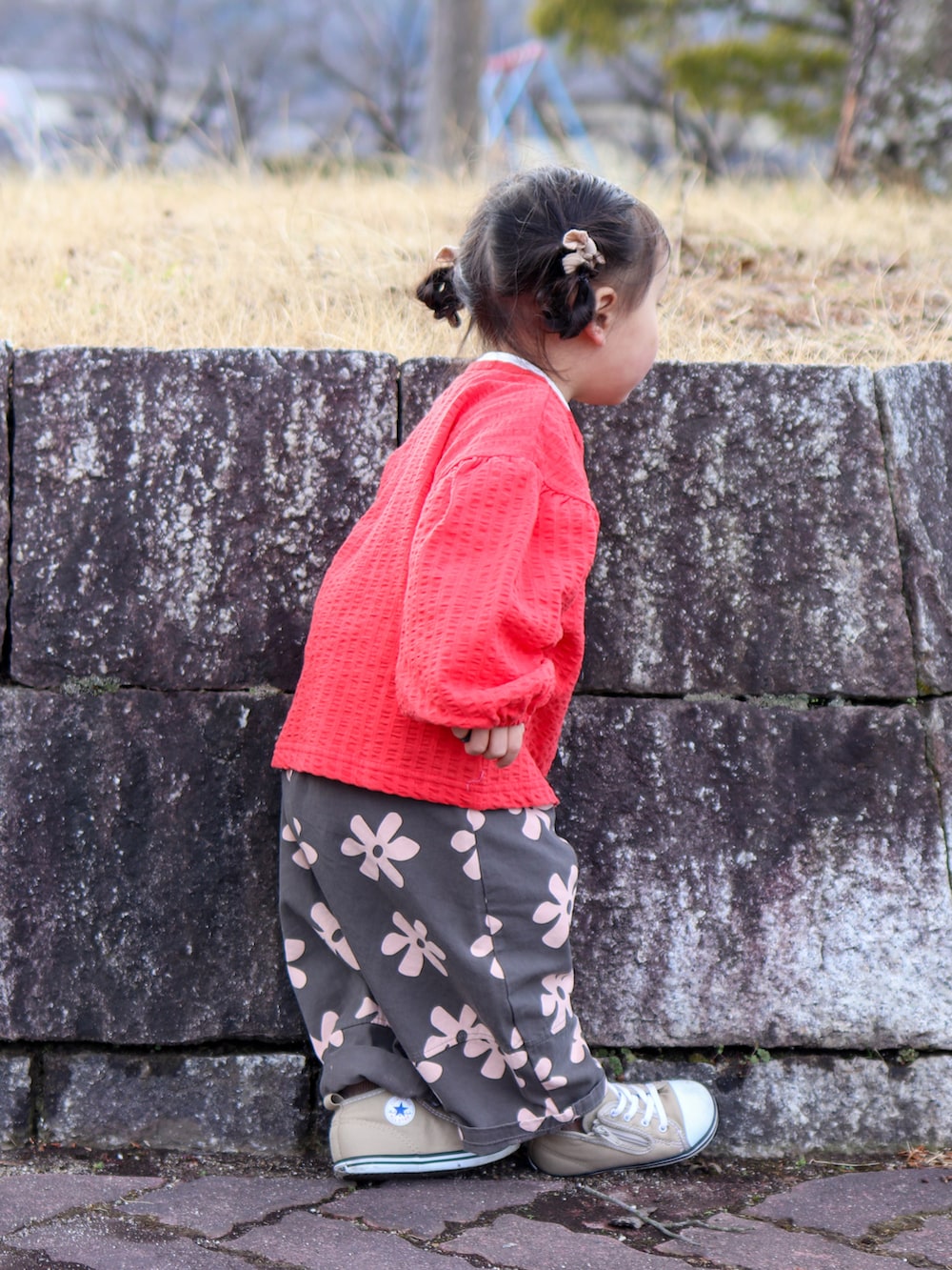 レッド系のカーディガン/ボレロ、グレー系のスラックス、ベージュ系のスニーカーを着用したキッズの春コーディネートの3枚目の写真