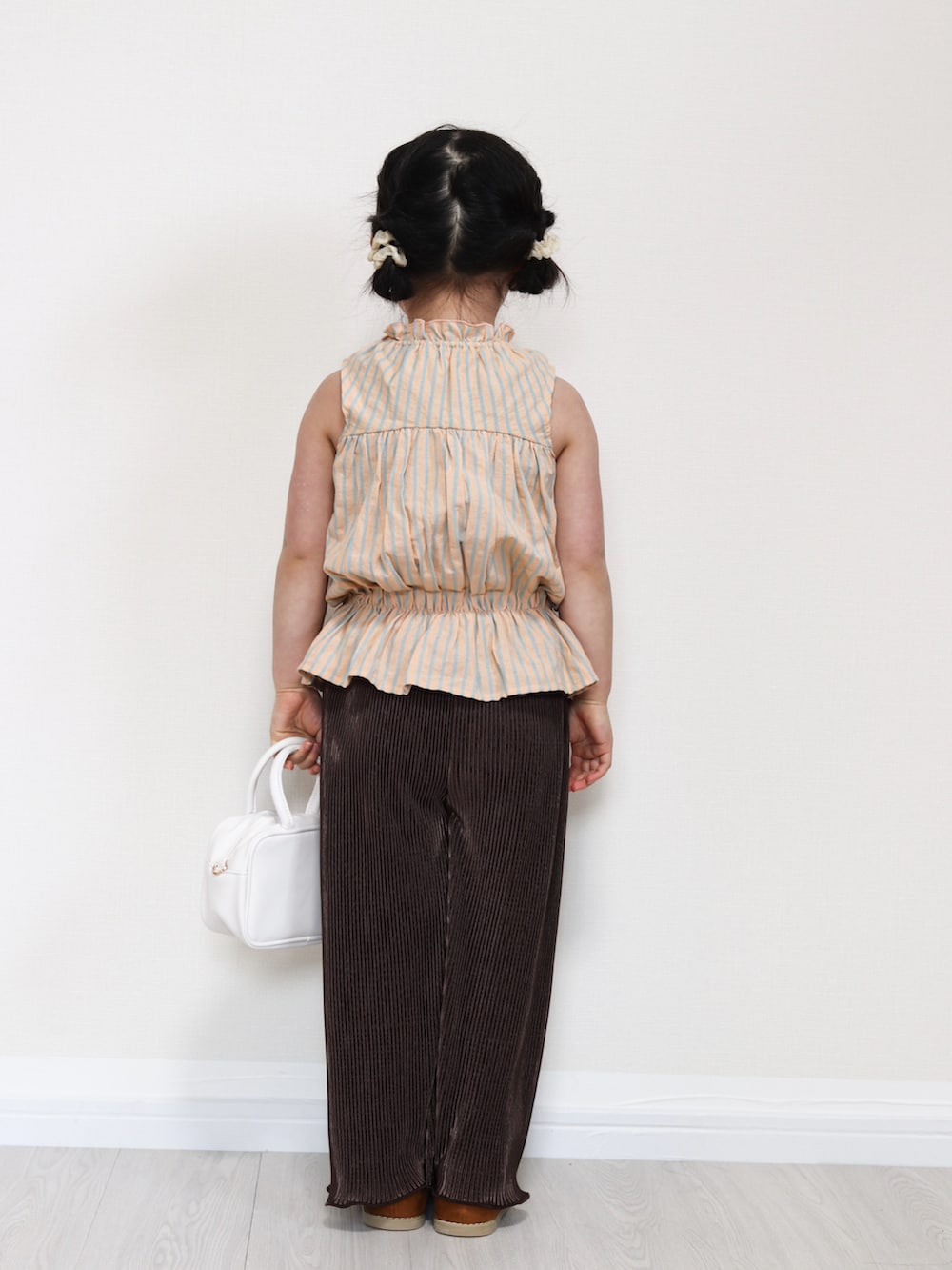 オレンジ系のセットアップ、ブラウン系のその他パンツ、イエロー系のサンダルを着用したキッズの春コーディネートの3枚目の写真