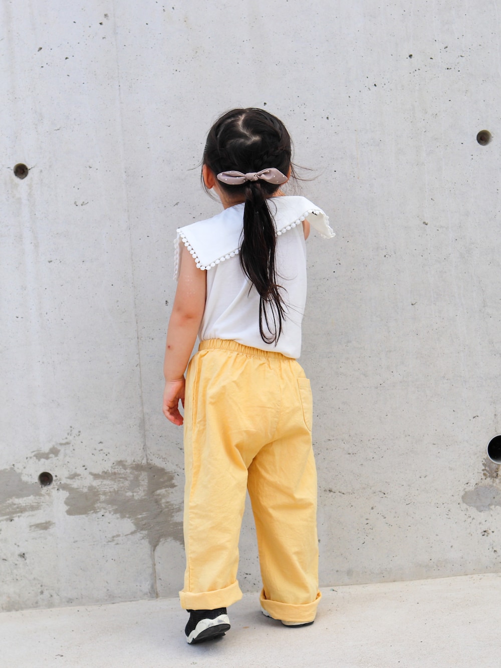 ホワイト系のTシャツ/カットソー、イエロー系のパンツ、ブラック系のスニーカーを着用したキッズの夏コーディネートの3枚目の写真