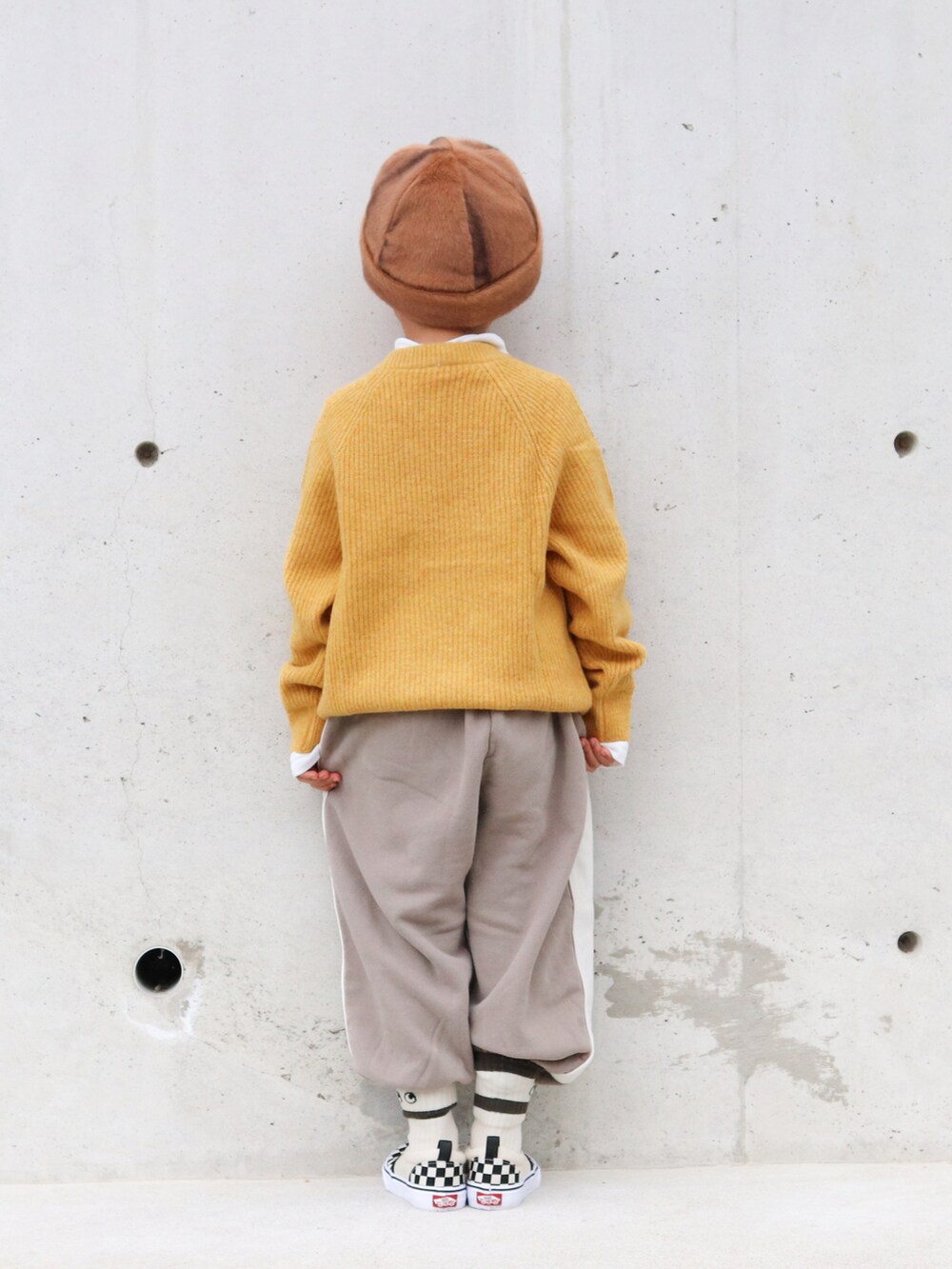 イエロー系のニット/セーター、ホワイト系のTシャツ/カットソー、ブラウン系のパンツを着用したキッズの冬コーディネートの3枚目の写真