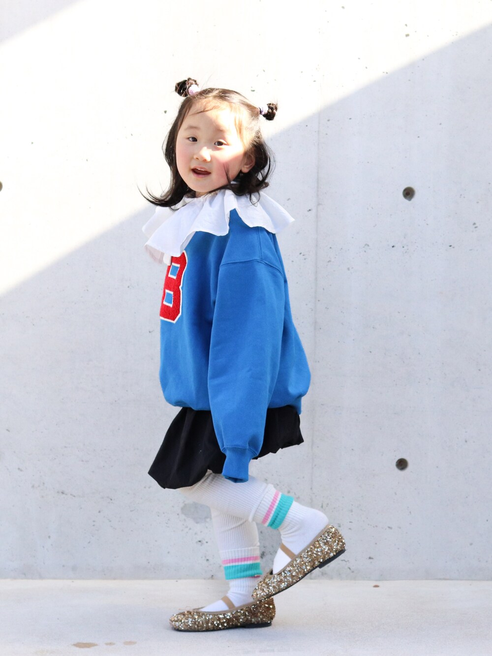 ブルー系のスウェット、ホワイト系のTシャツ/カットソー、ブラック系のスカートを着用したキッズの冬コーディネートの2枚目の写真