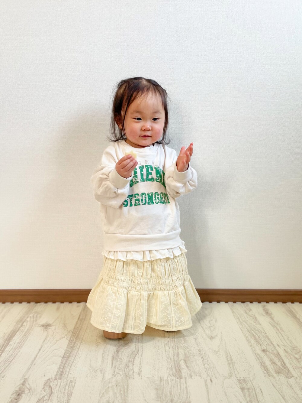 ホワイト系のスウェット、ベージュ系のスカート、ホワイト系のスニーカーを着用したキッズの春コーディネートの2枚目の写真