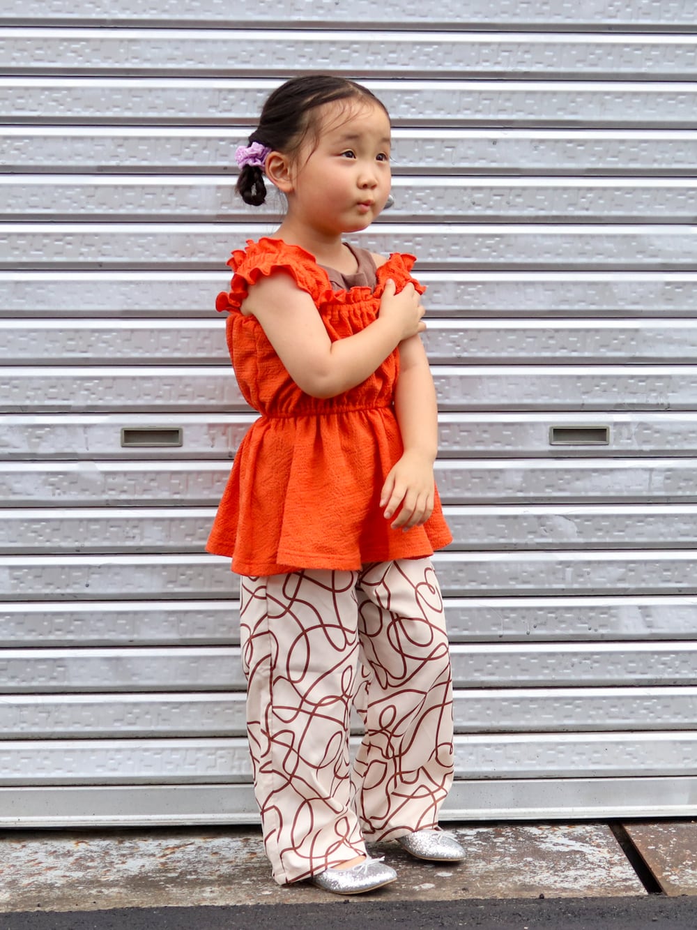 オレンジ系のキャミソール、ブラウン系のタンクトップ、ベージュ系のその他パンツを着用したキッズの夏コーディネートの2枚目の写真