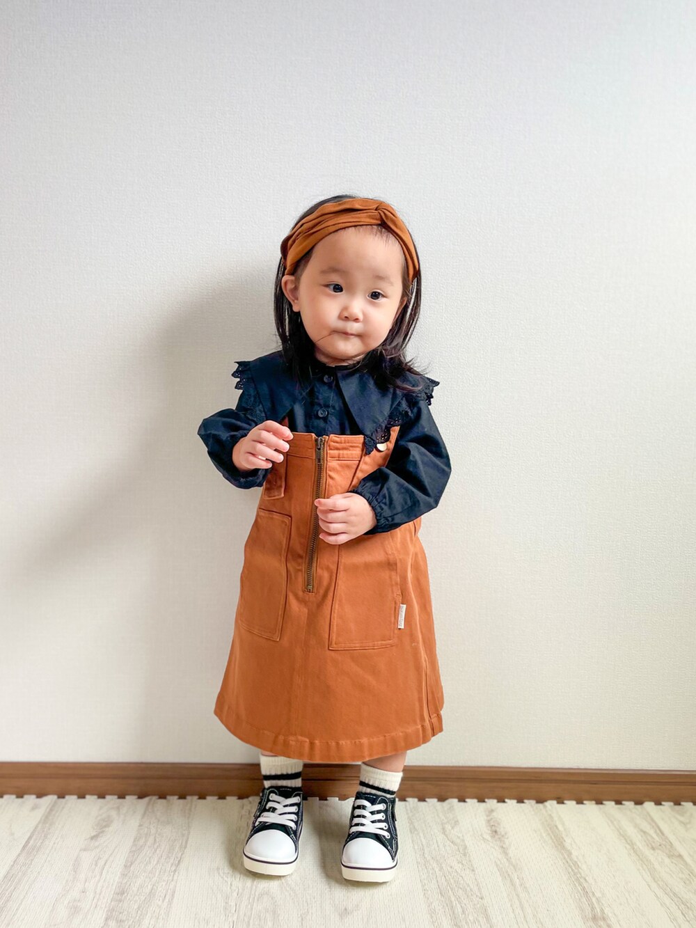 ブラック系のシャツ/ブラウス、イエロー系のジャンパースカート、ブラック系のスニーカーを着用したキッズの秋コーディネートの4枚目の写真