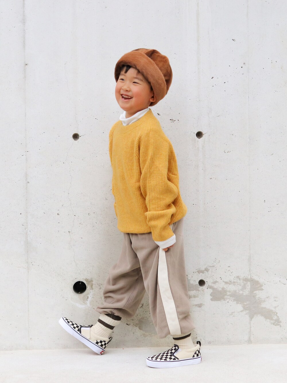 イエロー系のニット/セーター、ホワイト系のTシャツ/カットソー、ブラウン系のパンツを着用したキッズの冬コーディネートの2枚目の写真