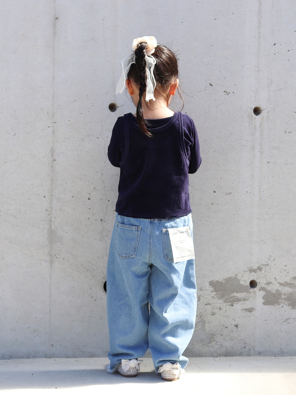 ブルー系のTシャツ/カットソー、ブルー系のデニムパンツ、ベージュ系のバレエシューズを着用したキッズの秋コーディネートの3枚目の写真