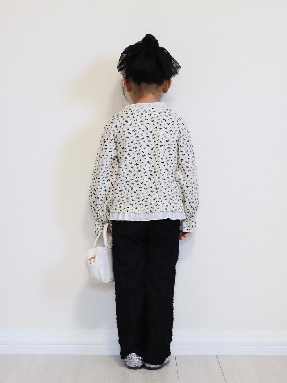 ホワイト系のカーディガン/ボレロ、シルバー系のバレエシューズ、ブラック系のその他パンツを着用したキッズの秋コーディネートの4枚目の写真