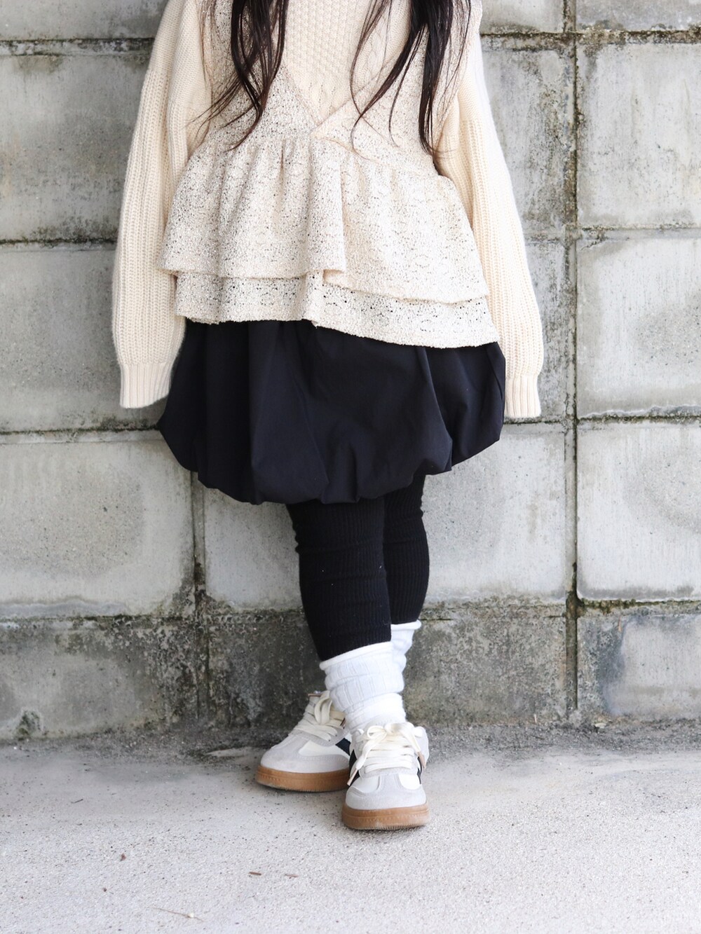 ホワイト系のニット/セーター、ベージュ系のベスト、ブラック系のスカートを着用したキッズの冬コーディネートの5枚目の写真