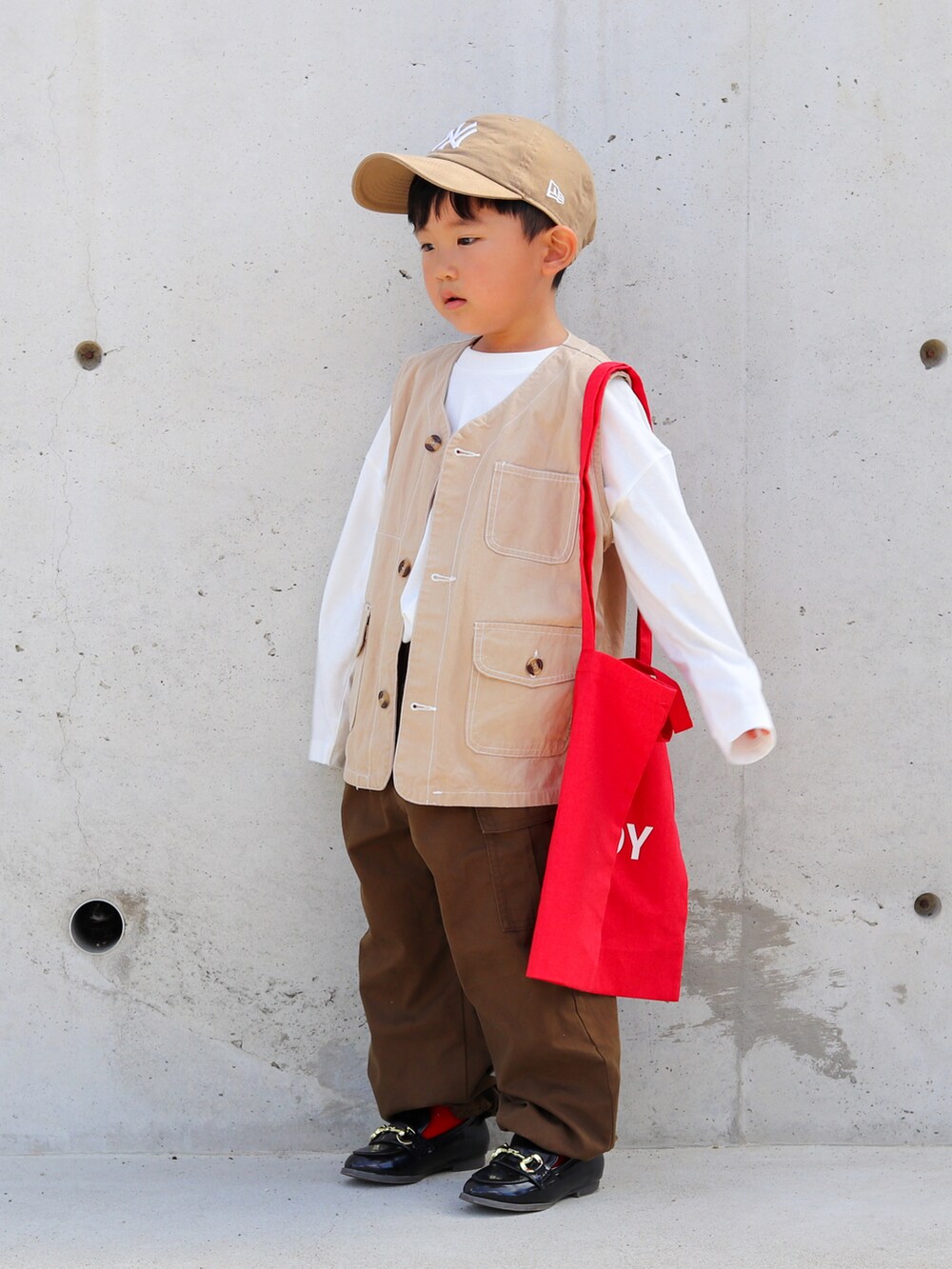 ホワイト系のTシャツ/カットソー、ベージュ系のベスト、ブラウン系のカーゴパンツを着用したキッズの秋コーディネートの2枚目の写真