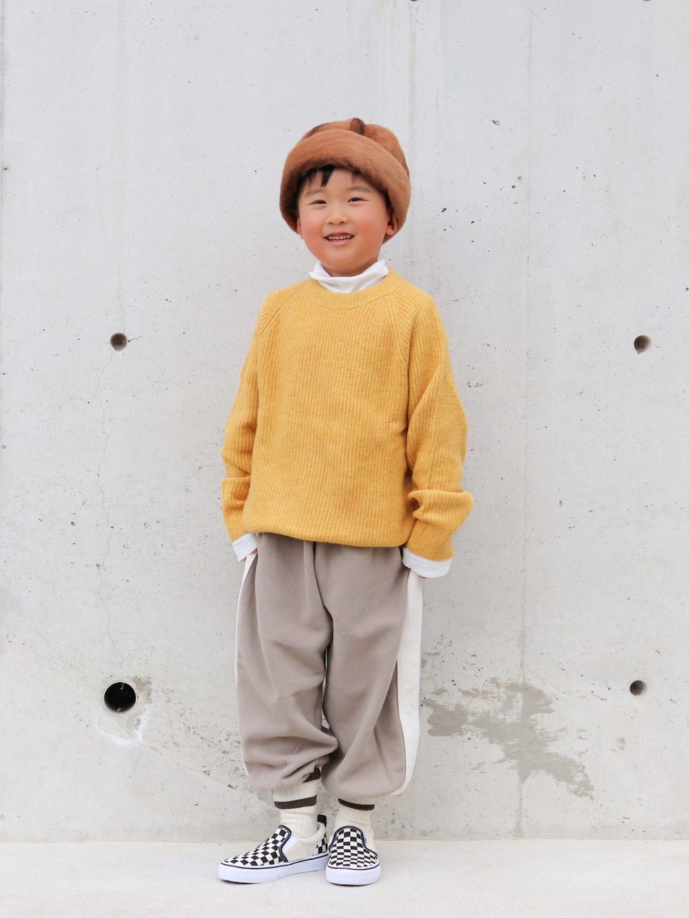 イエロー系のニット/セーター、ホワイト系のTシャツ/カットソー、ブラウン系のパンツを着用したキッズの冬コーディネートの4枚目の写真
